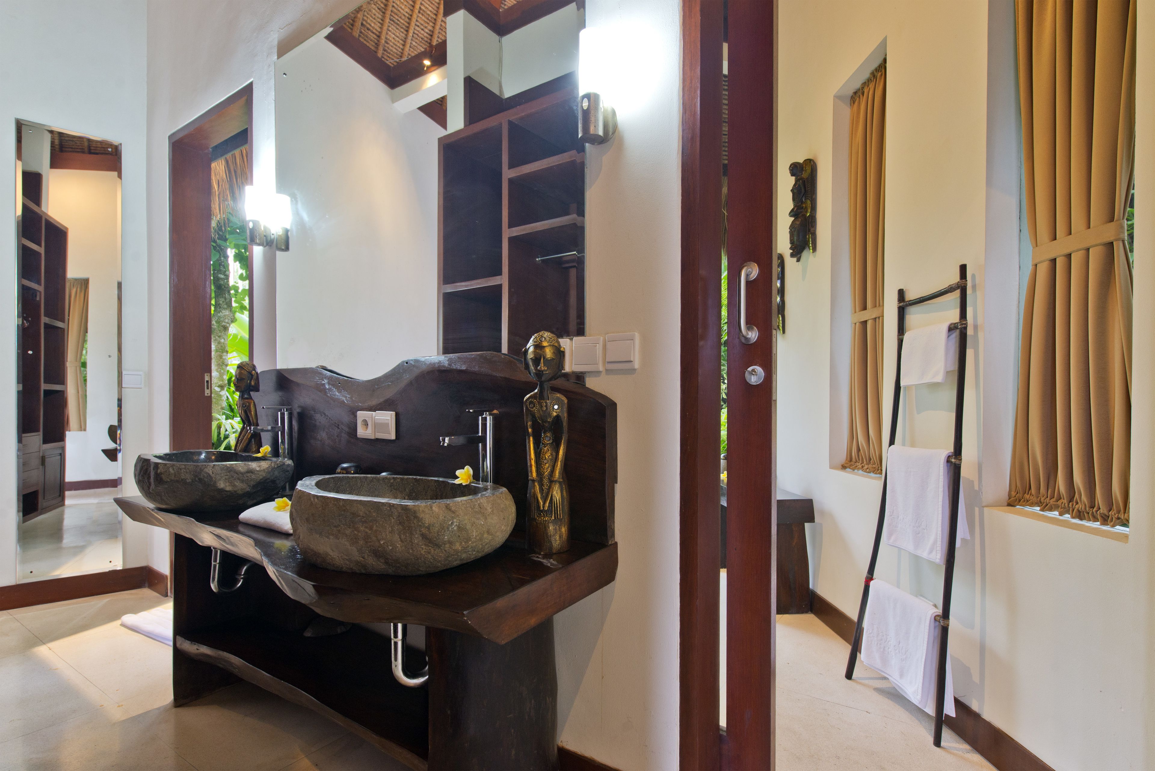 A bathroom with a stone sink, a mirror, and a towel rack.