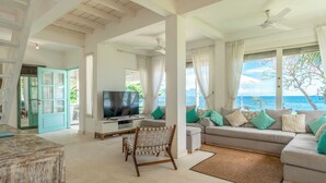 Un salón amplio con televisor grande, asientos cómodos y vista al océano.