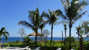 A poolside area with lounge chairs and a view of the ocean.