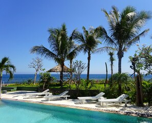 A poolside area with lounge chairs and a view of the ocean.