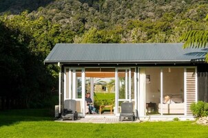 Uma casa moderna com varanda coberta, grandes janelas e vista para uma paisagem verde exuberante.