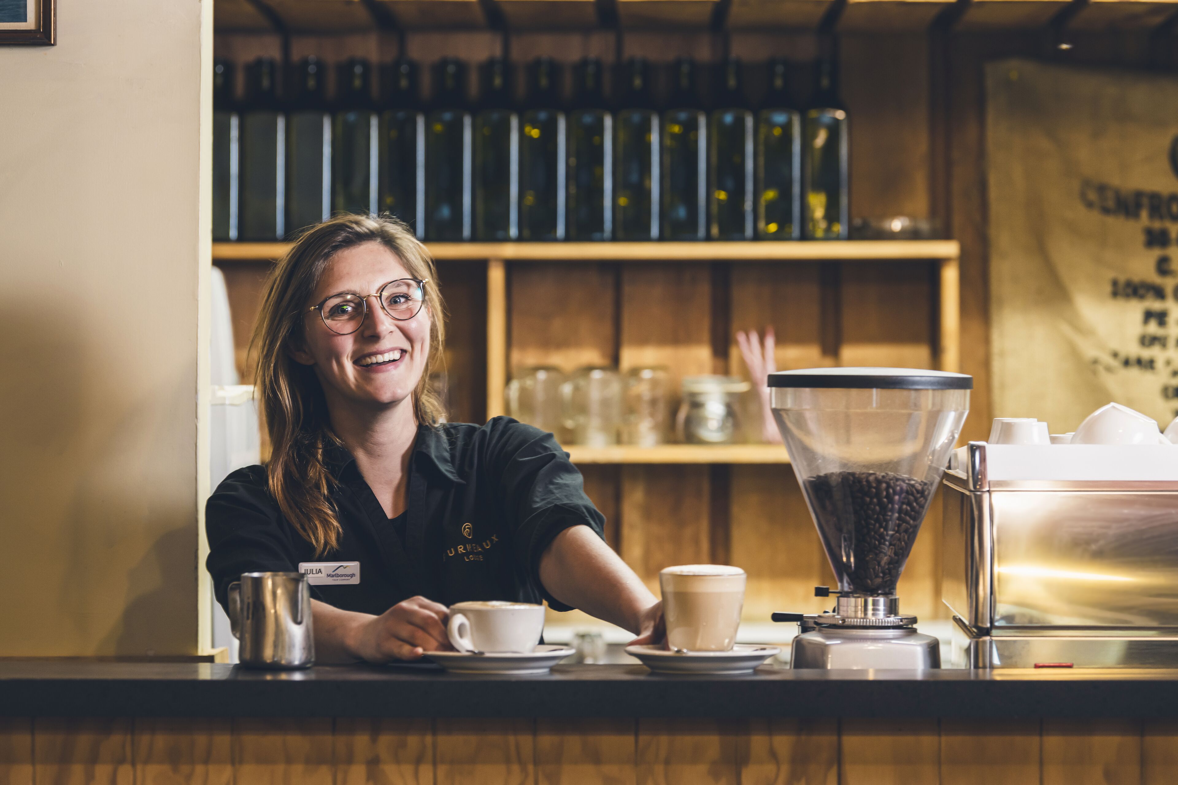Un barista en una estación de café con una máquina de café, tazas y un molinillo.