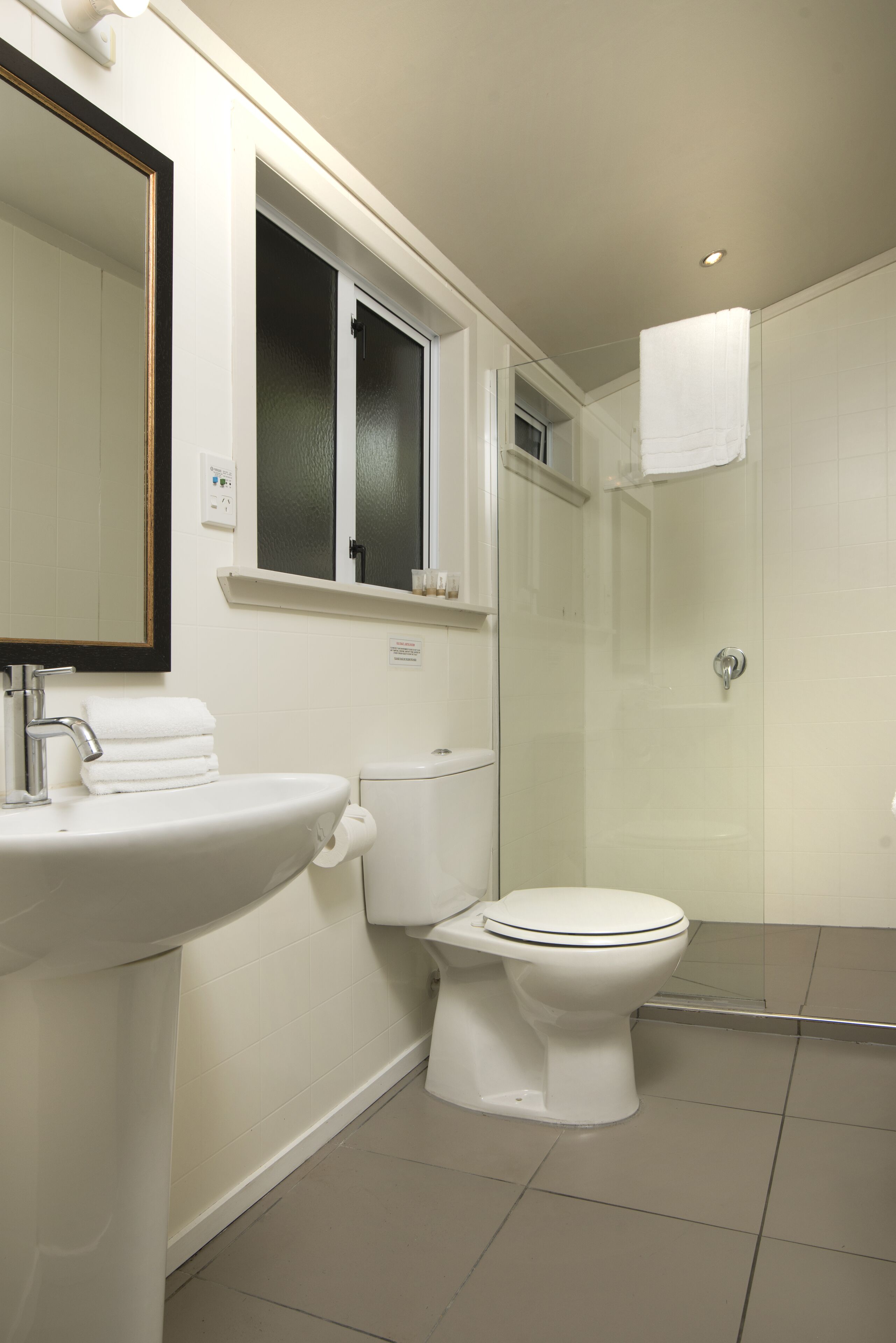 Un baño moderno con lavabo, inodoro y cabina de ducha de vidrio.
