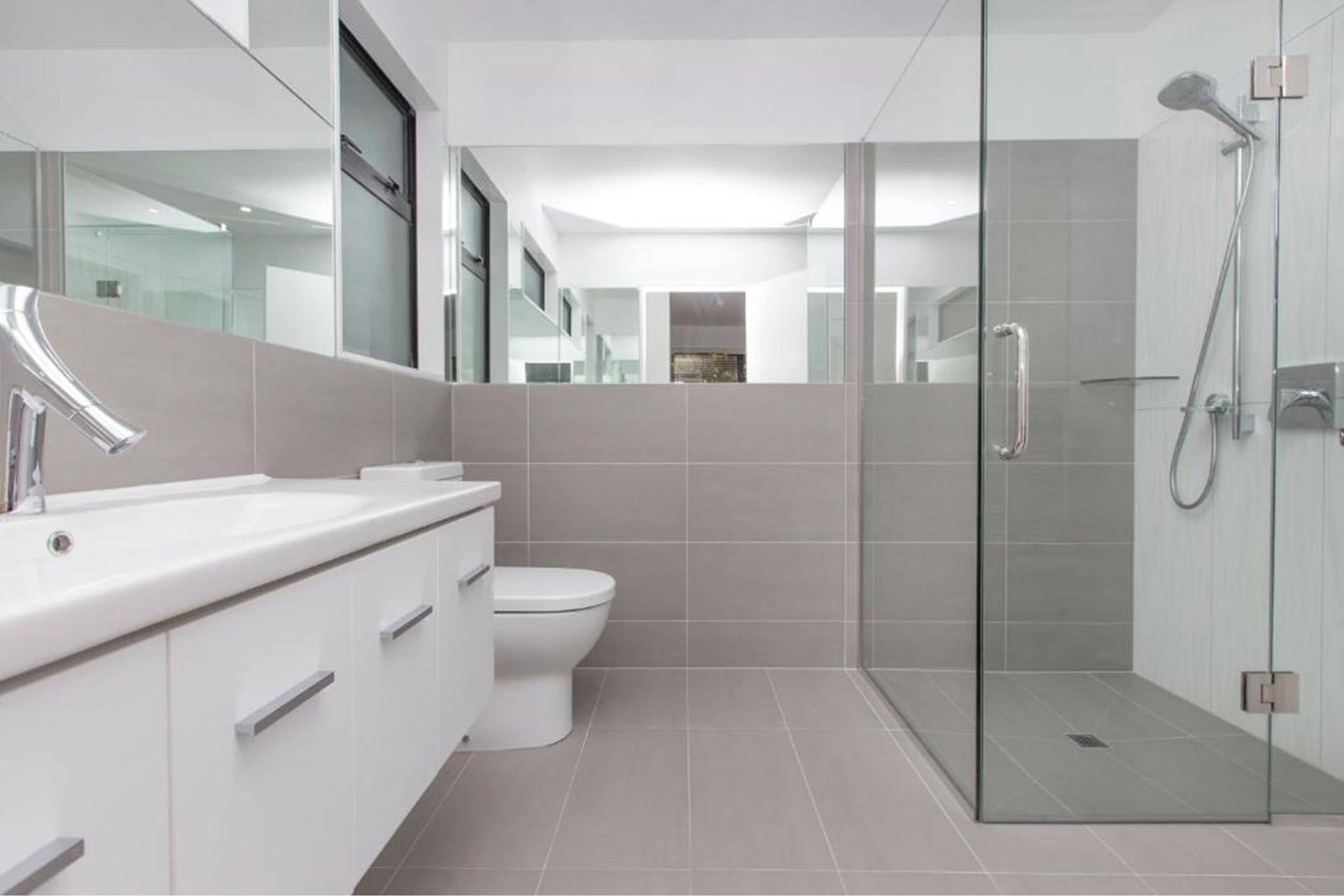 A modern bathroom with a glass shower enclosure, a white sink, and a toilet.