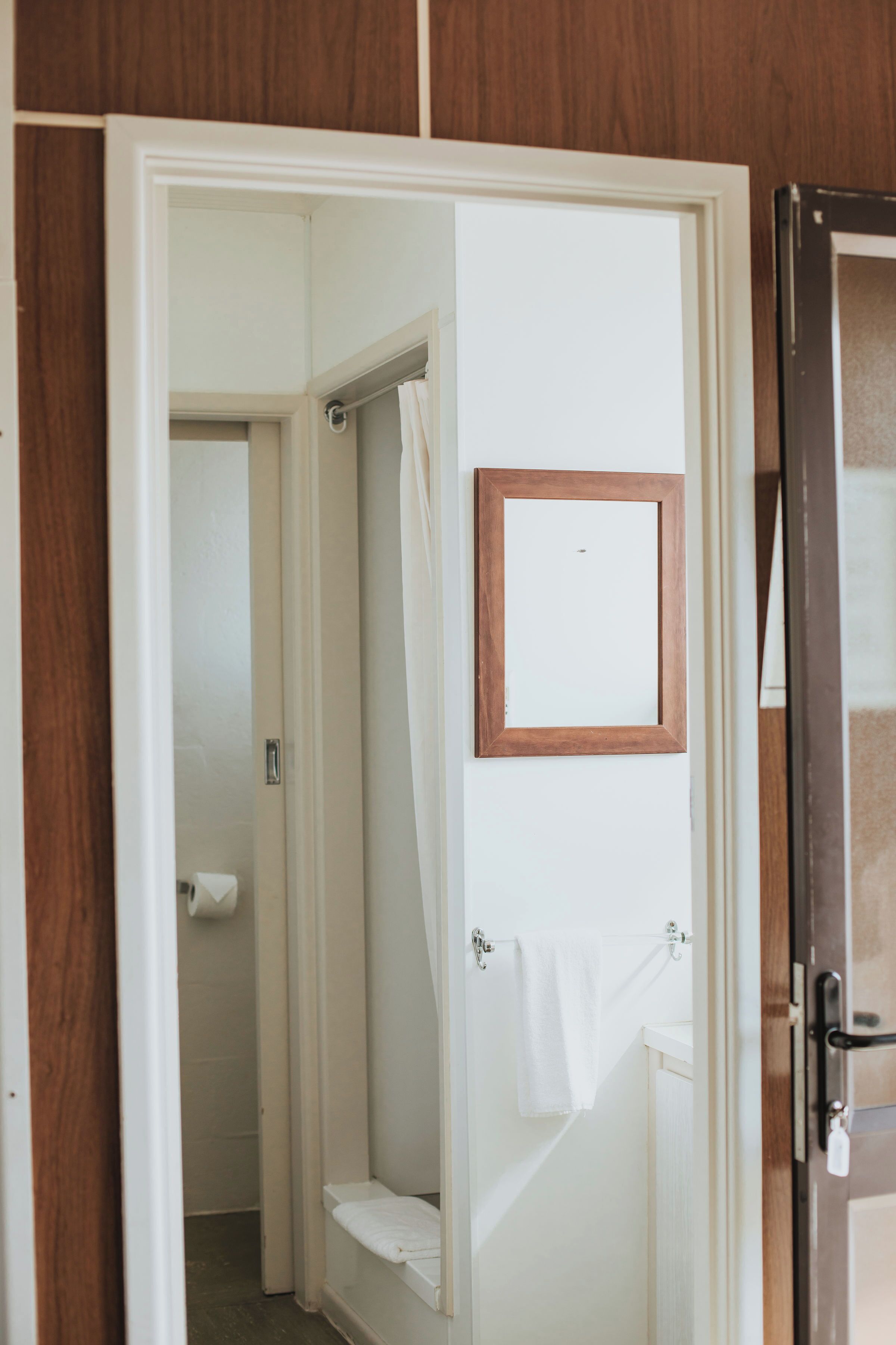 Un baño con ducha, inodoro y un espejo enmarcado en la pared.