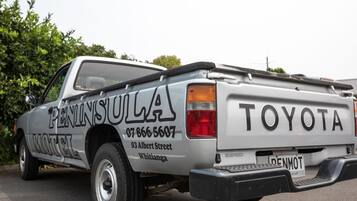 A silver Toyota pickup truck with "PENINSULULA" and a phone number on the side.