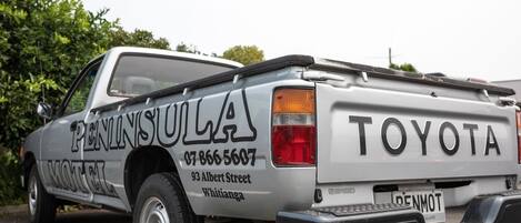 Una camioneta Toyota plateada con la leyenda "PENINSULULA" y un número de teléfono en la carrocería.