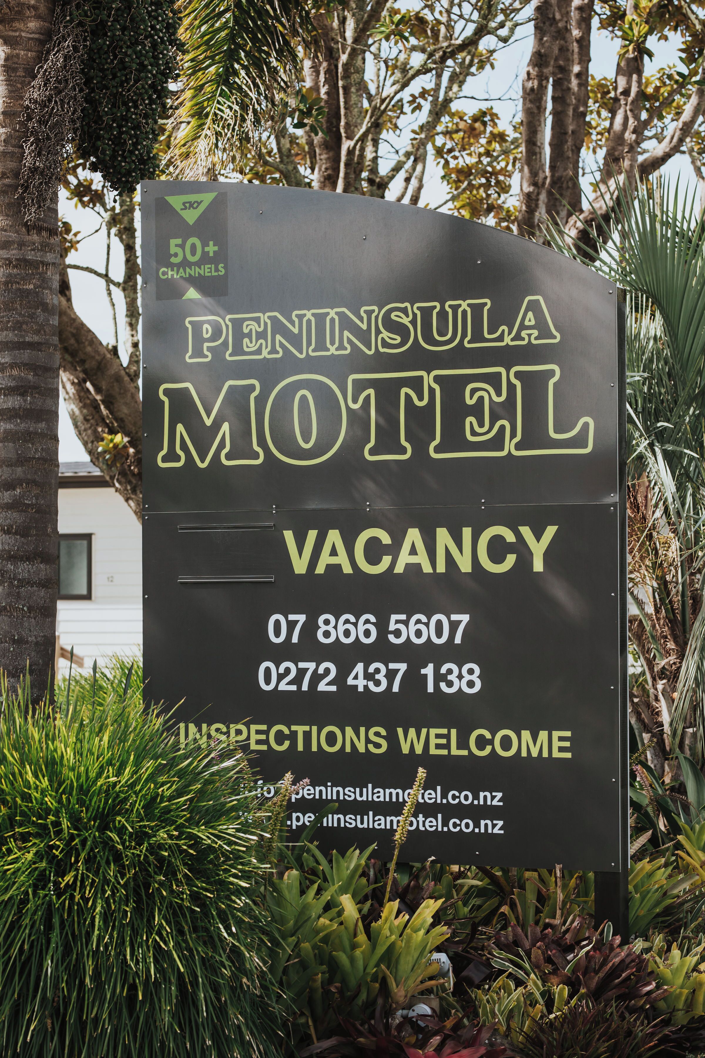 Schild des Peninsula Motel, das eine freie Unterkunft bewirbt, mit Kontaktdaten und einer Website-URL.