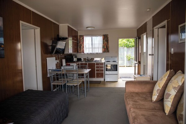 Un espacio habitable compacto con kitchenette, comedor y sofá.