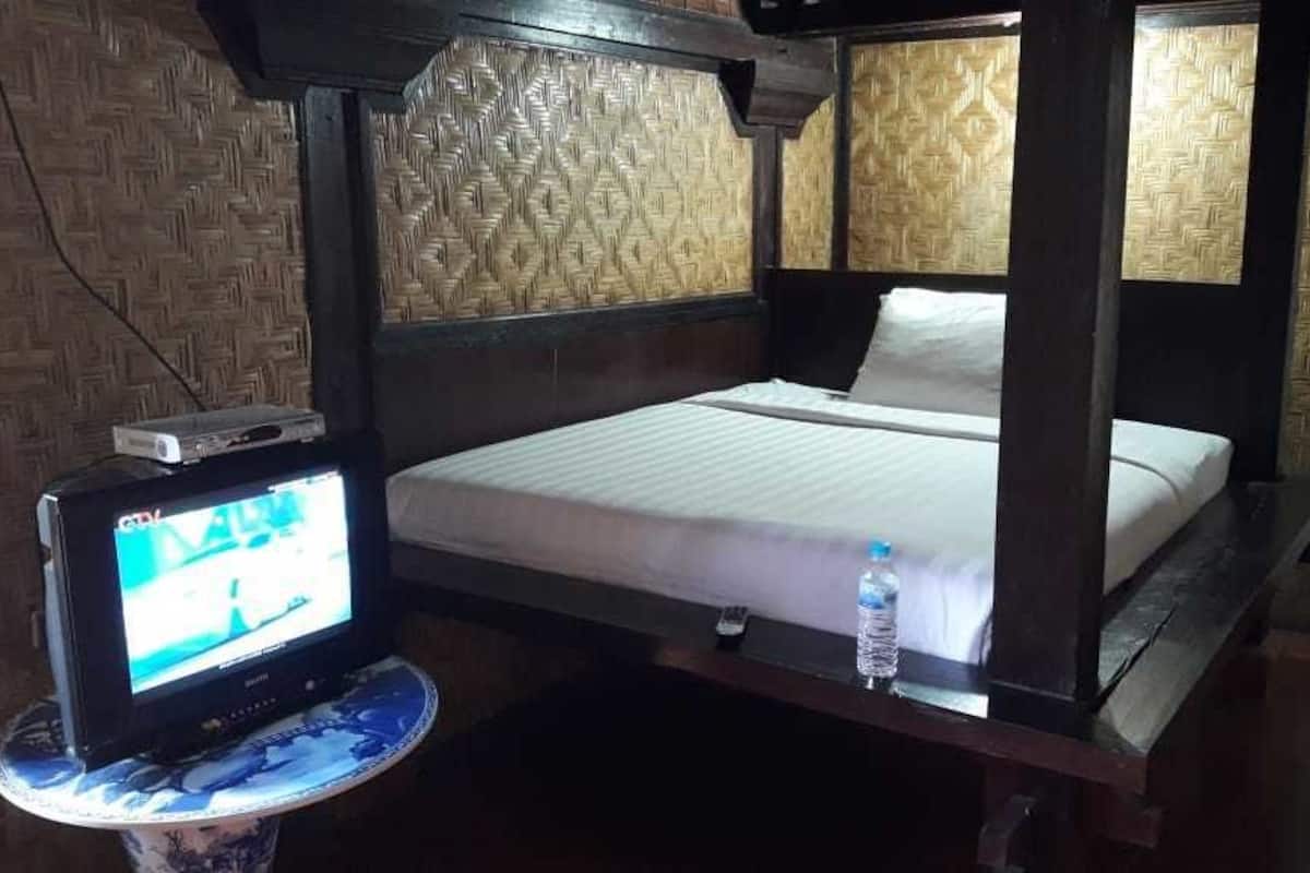 A four-poster bed with a television on a small table beside it.