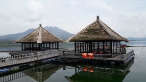 Two thatched-roof structures with a view of mountains in the background. - Batur Lakeside Huts (Kintamani)