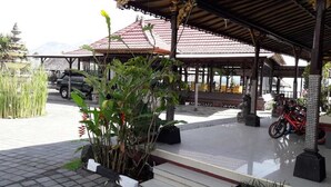 A covered pavilion with a tiled roof, a fountain, and a parked motorcycle. - Batur Lakeside Huts (Kintamani)