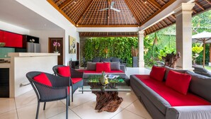 A modern living area with a glass coffee table, wicker chairs, and a sofa with red cushions.