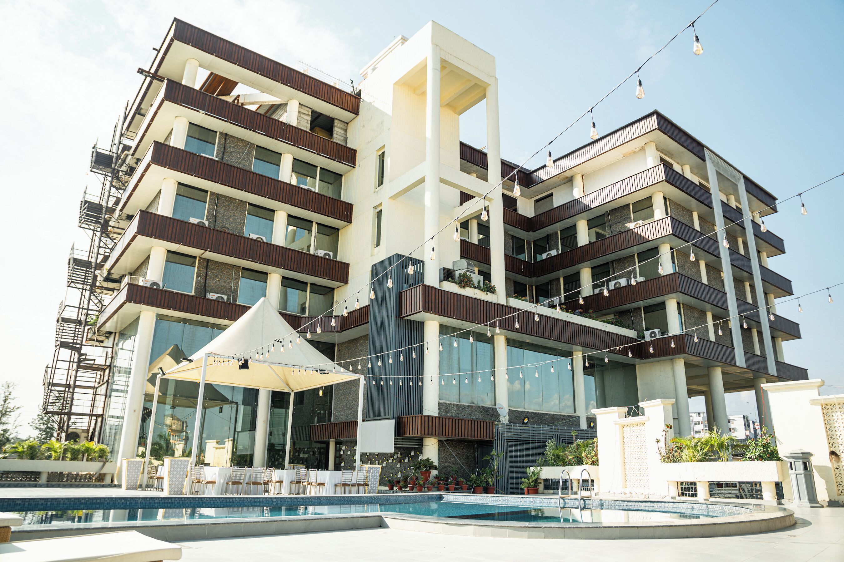 A multi-story hotel with balconies, a swimming pool, and outdoor seating.