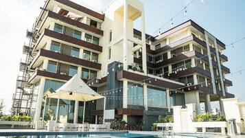 A multi-story hotel with balconies, a swimming pool, and outdoor seating.