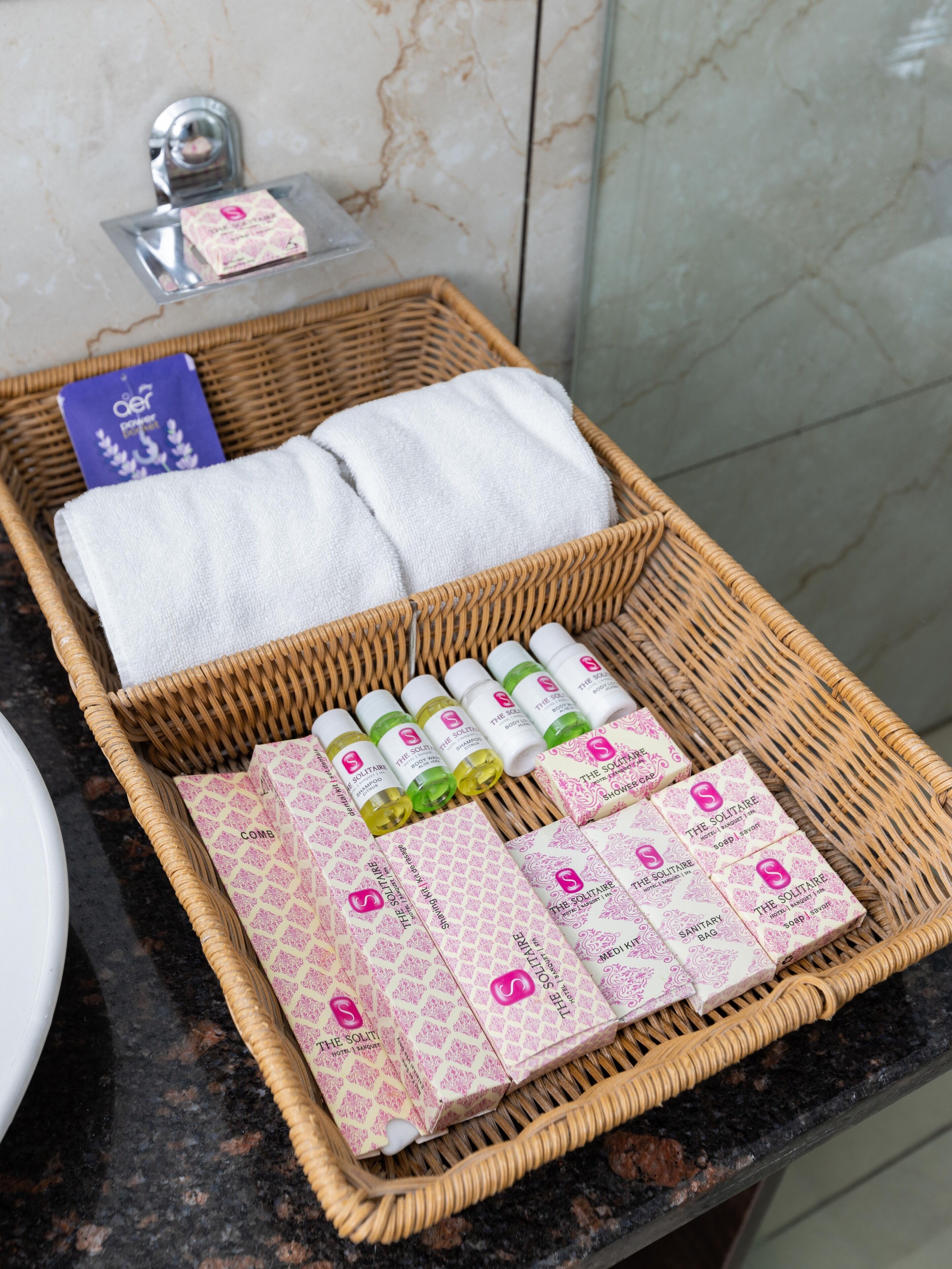A wicker basket on a bathroom counter containing toiletries and towels.