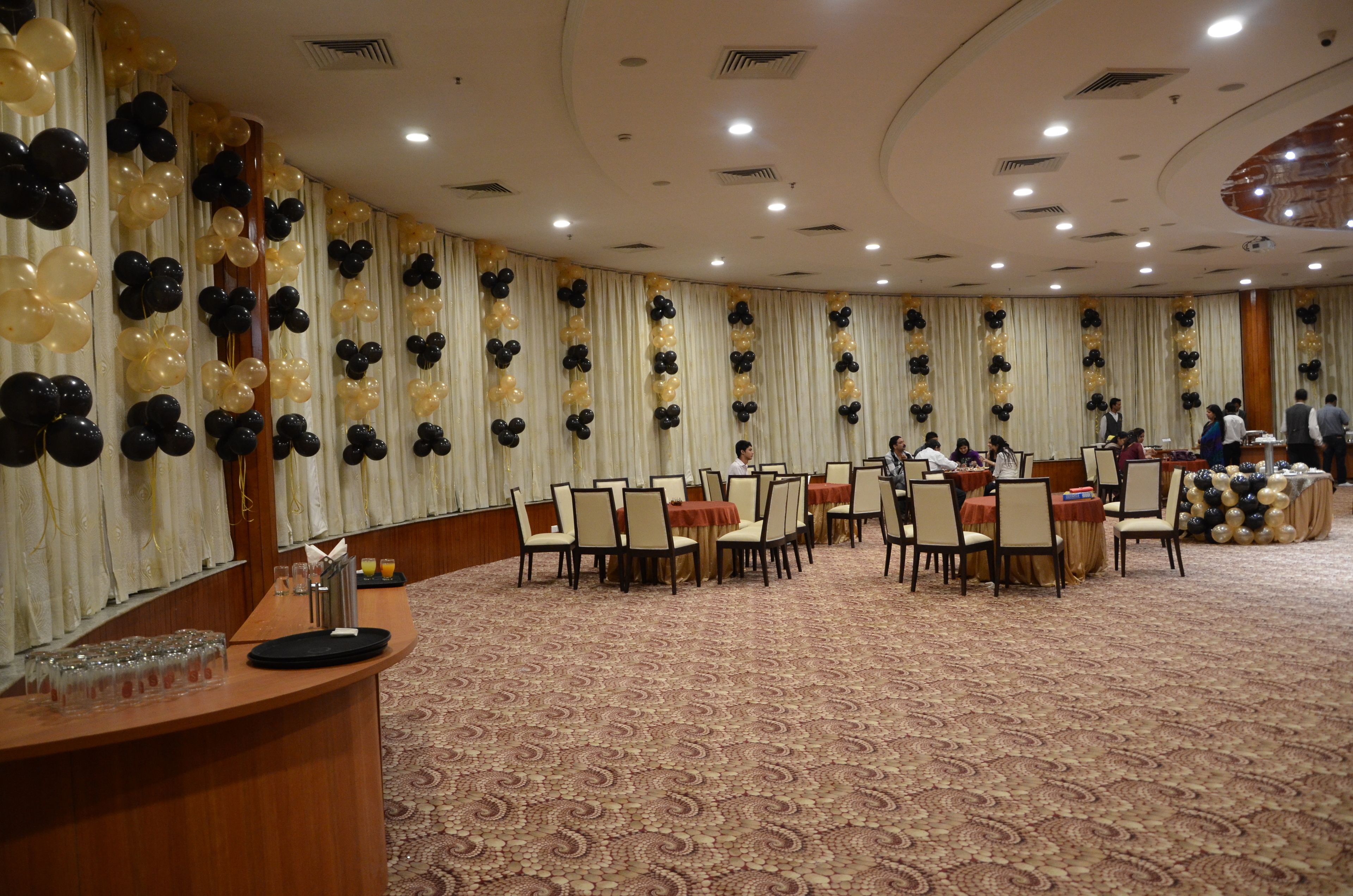 A banquet hall with round tables and chairs, a reception desk, and a patterned carpet.