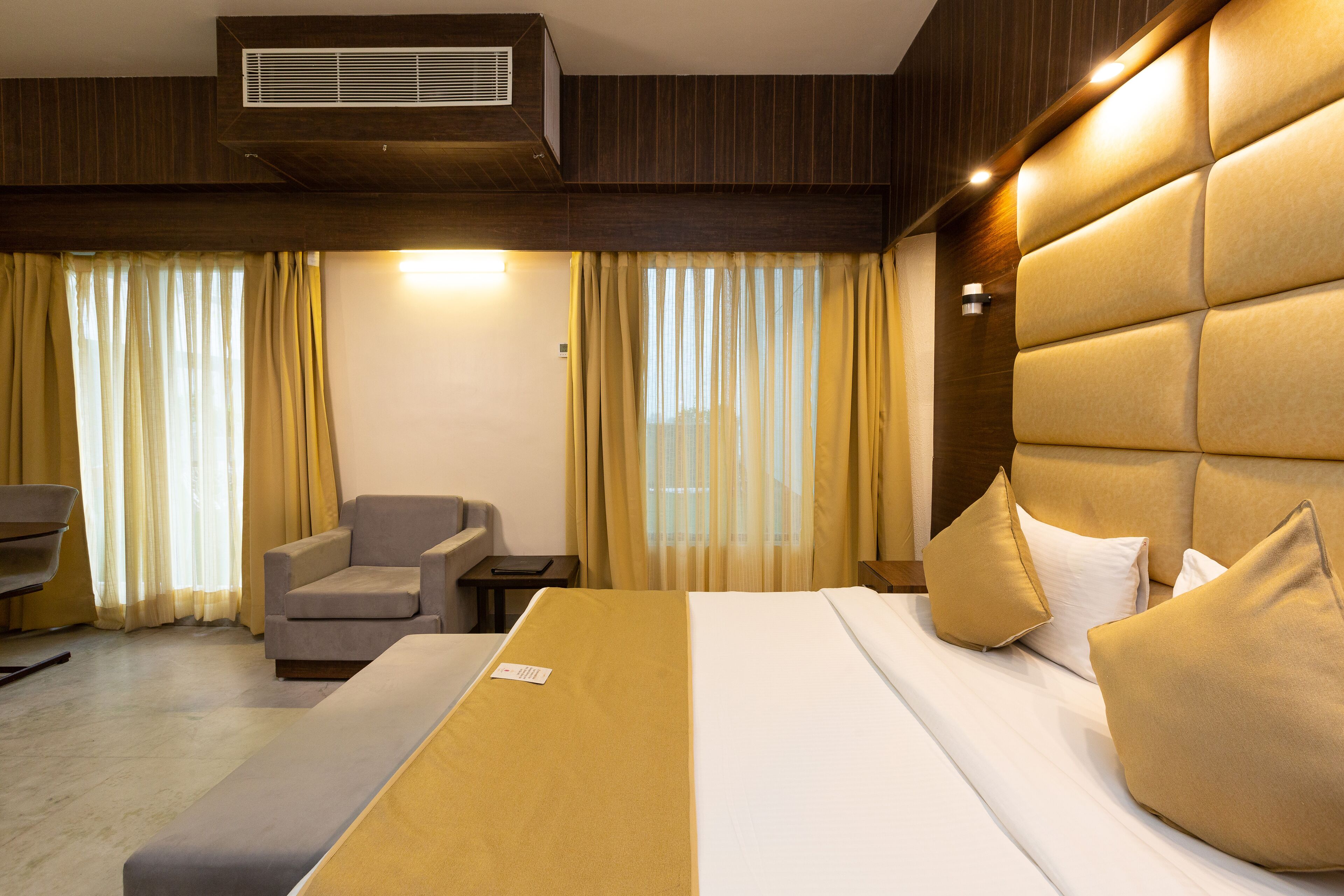 A hotel room with a large bed, a sofa, a chair, and a desk.