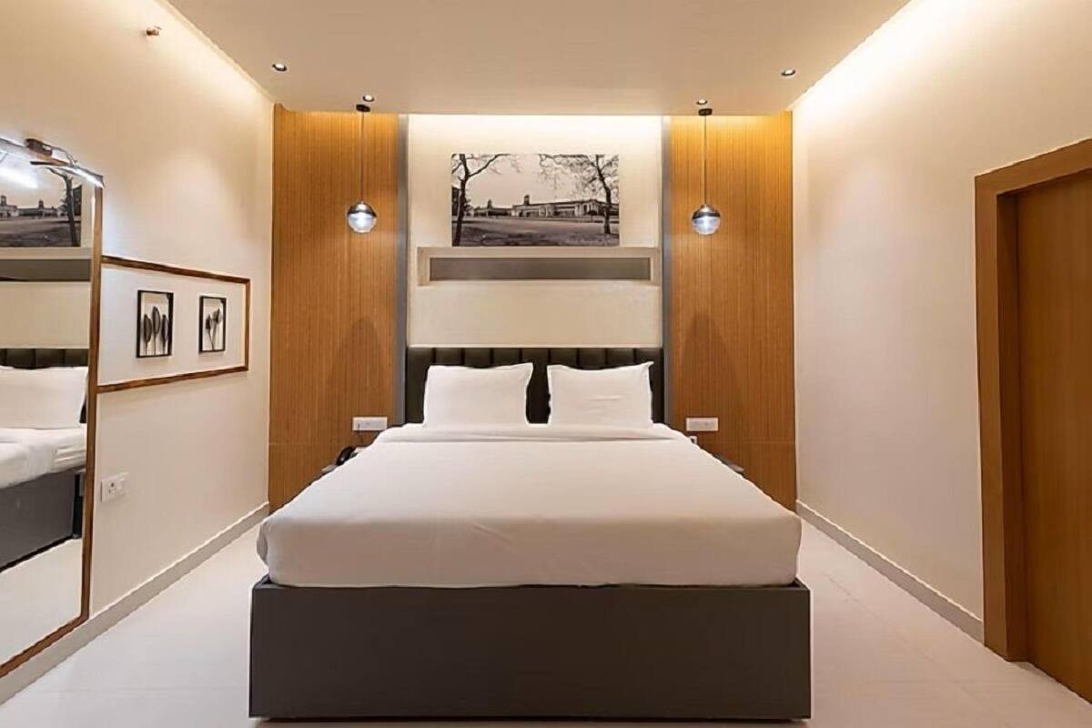 A modern bedroom with a large bed, wooden paneling, and a framed picture on the wall.