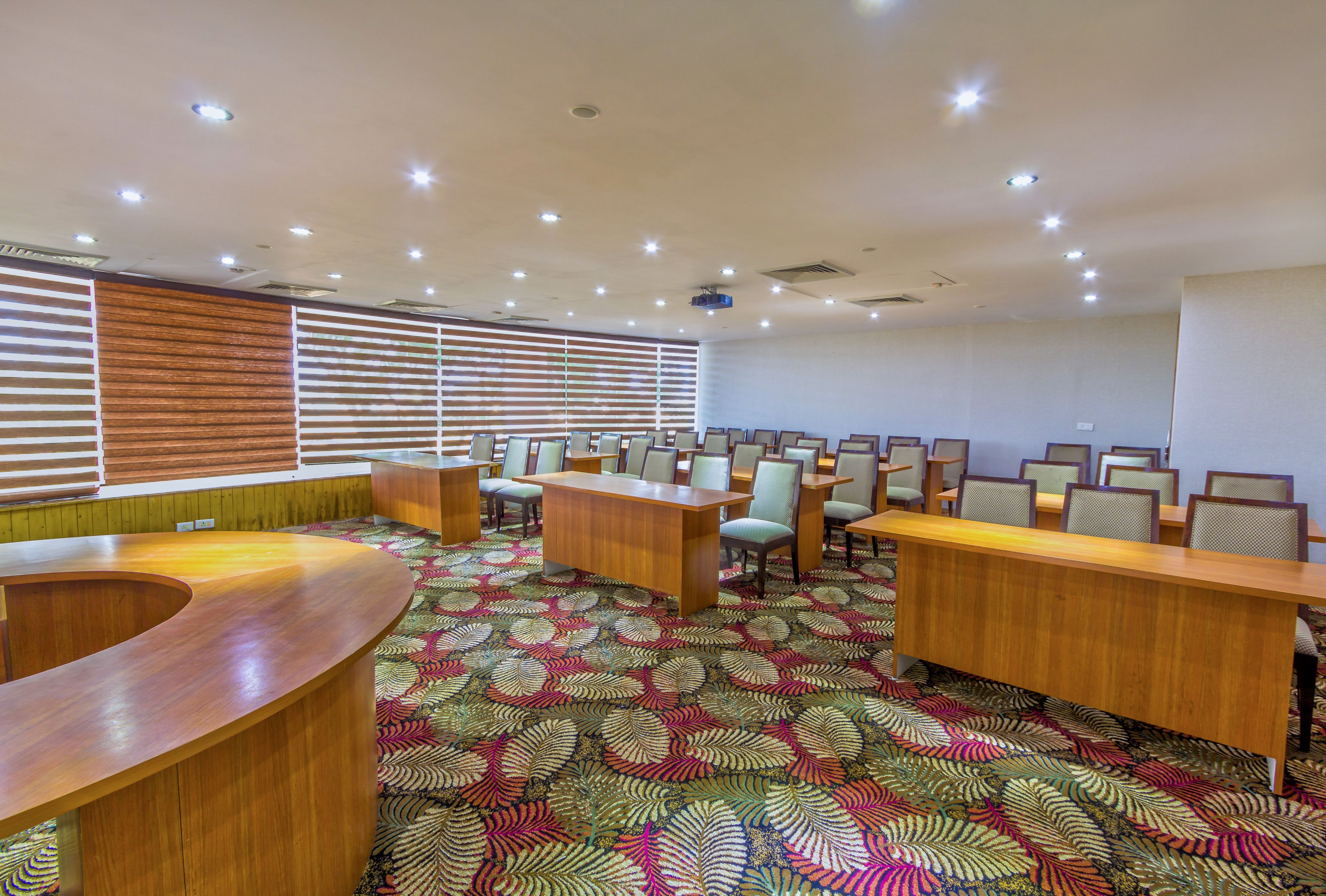 Una sala de conferencias con una larga mesa, múltiples sillas y una alfombra estampada.