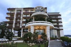 Un hotel de varios pisos con un atrio central, zona de estar al aire libre y un vehículo en la entrada.