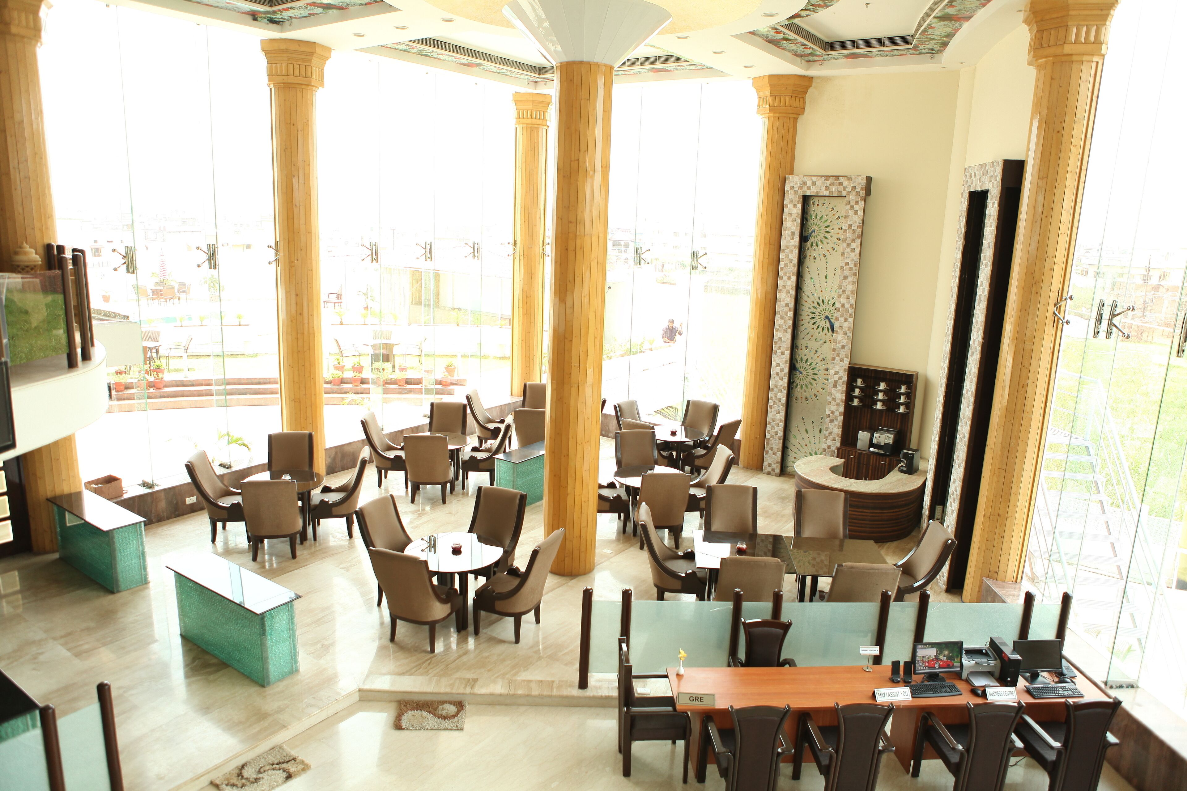 Un hall d’hôtel spacieux, doté de plusieurs espaces salon, de grandes fenêtres et d’un comptoir d’accueil central.