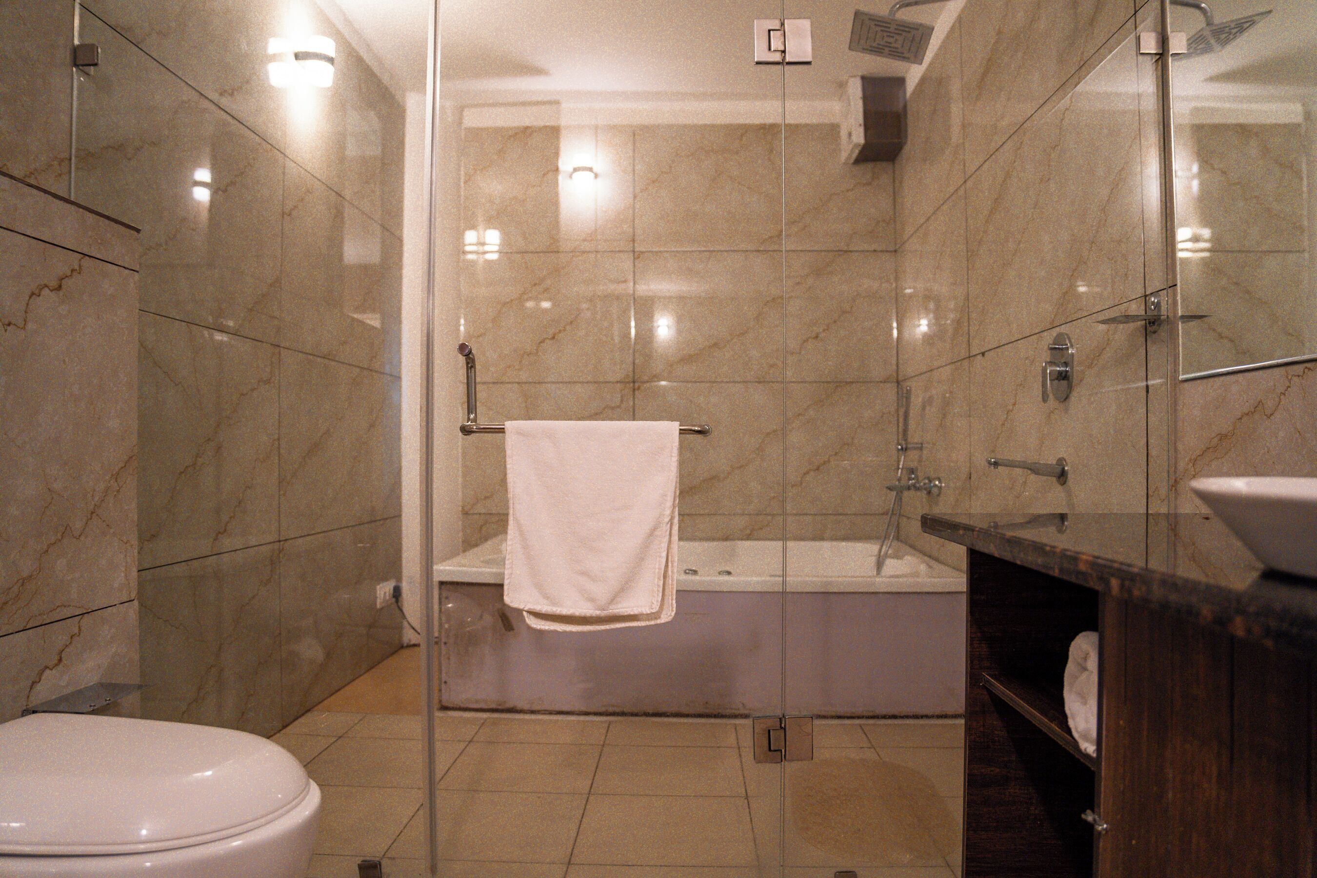 A bathroom with a glass-enclosed shower, a white toilet, and a dark wooden vanity with a sink.