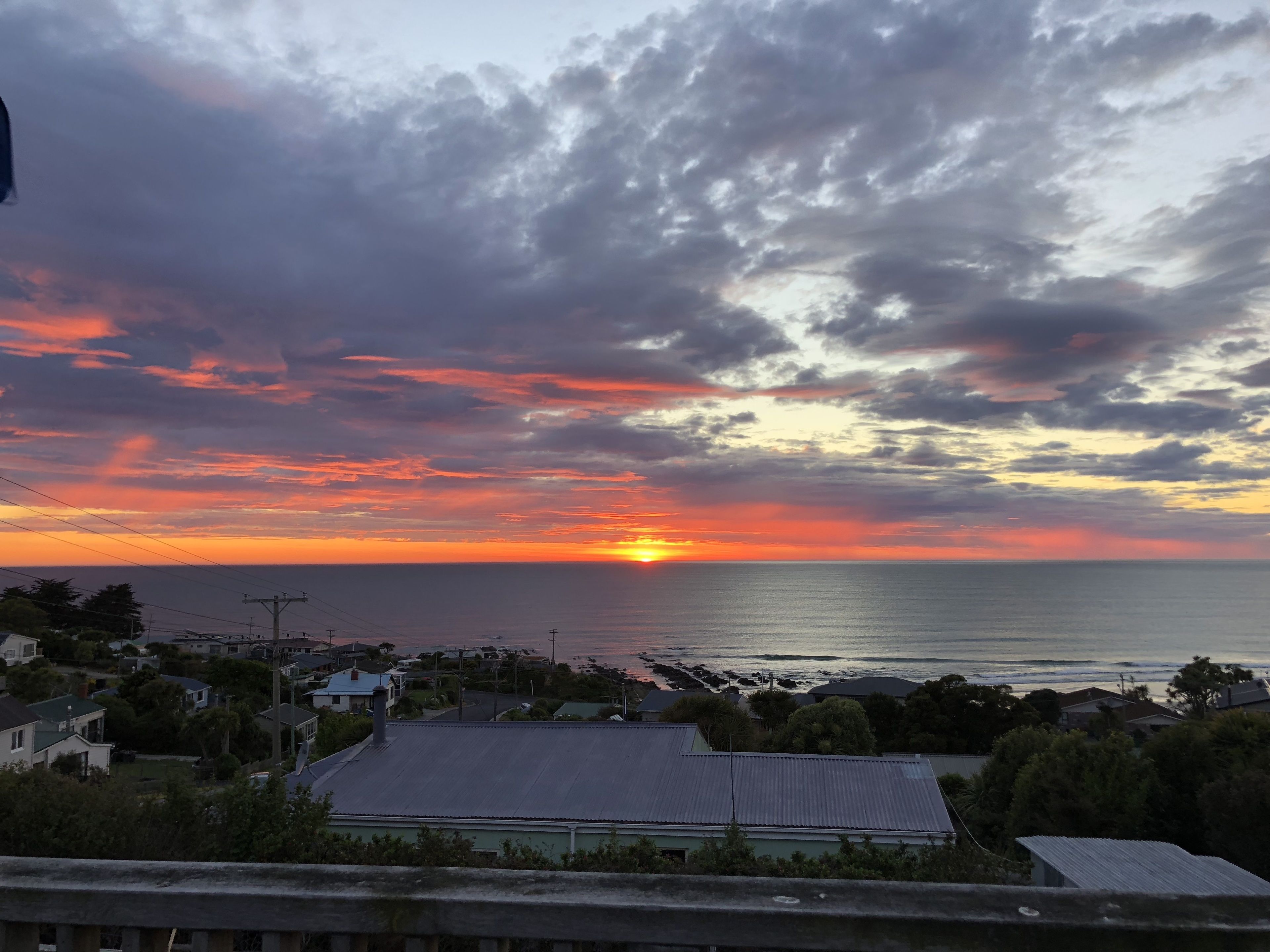 Vista del atardecer en la costa, con casas y cielo despejado.