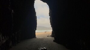 A beach view through a natural rock archway. - The Kaka Point Motels (Kaka Point)