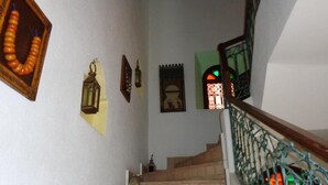 Un escalier orné d’une rampe en fer forgé, une lanterne et un tableau encadré accroché au mur.