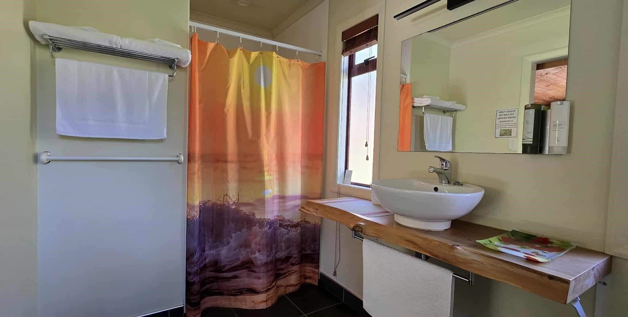 Un baño con cortina de ducha, lavamanos y perchero.