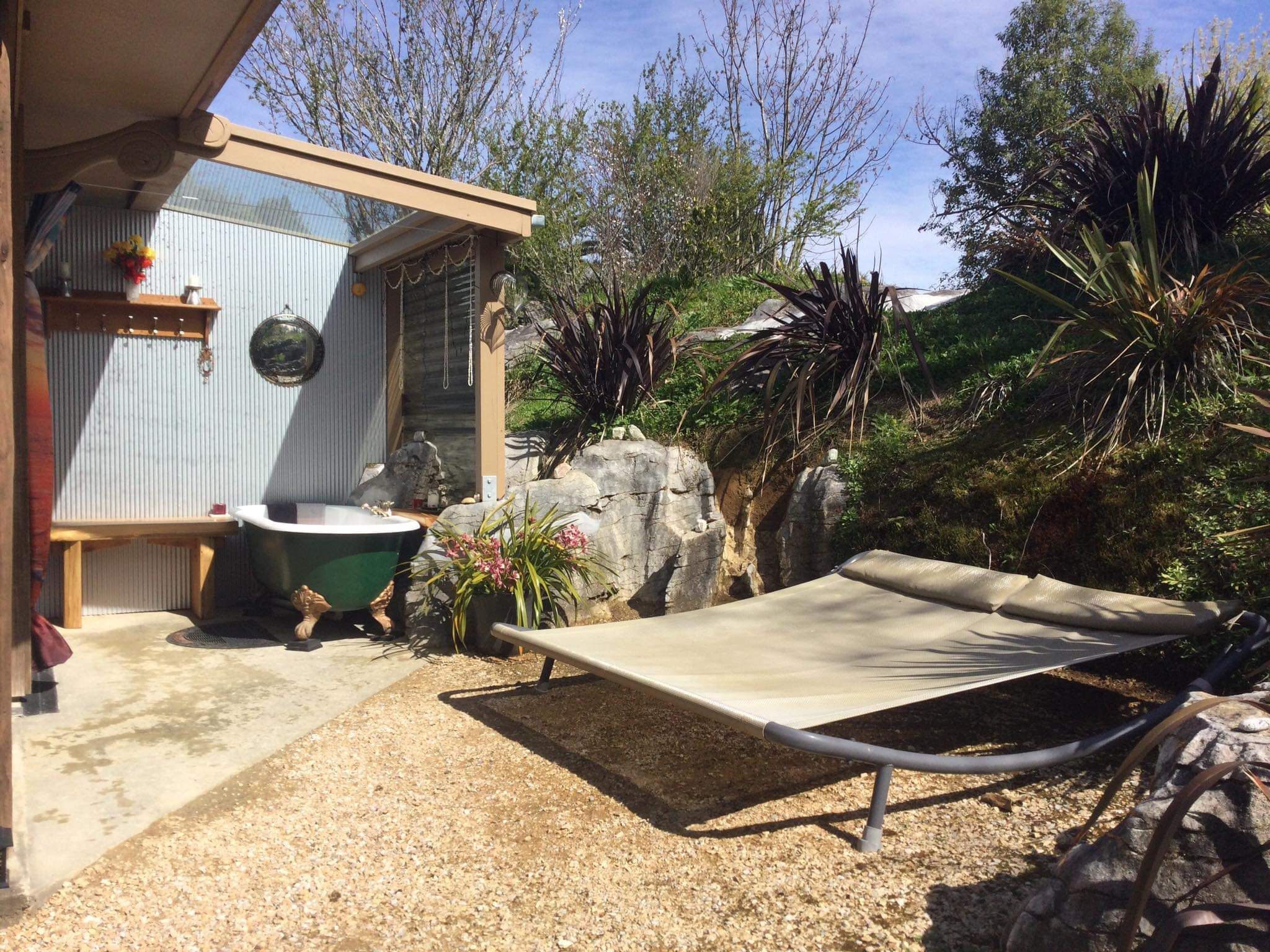 Una casa pequeña con jardín, una bañera verde y una silla de descanso.