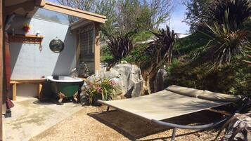 Una casa pequeña con jardín, una bañera verde y una silla de descanso.
