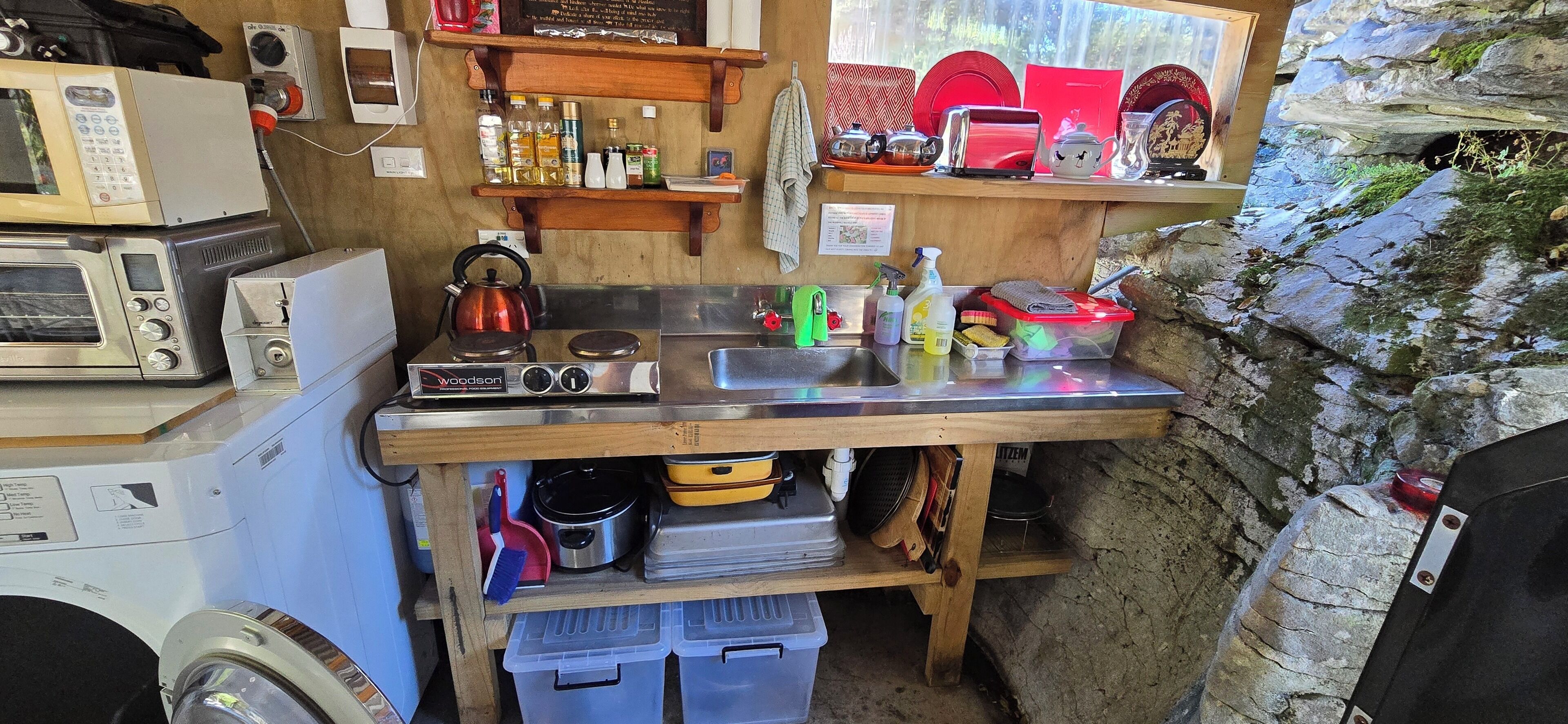 Uma cozinha compacta com micro-ondas, chaleira e diversos utensílios.