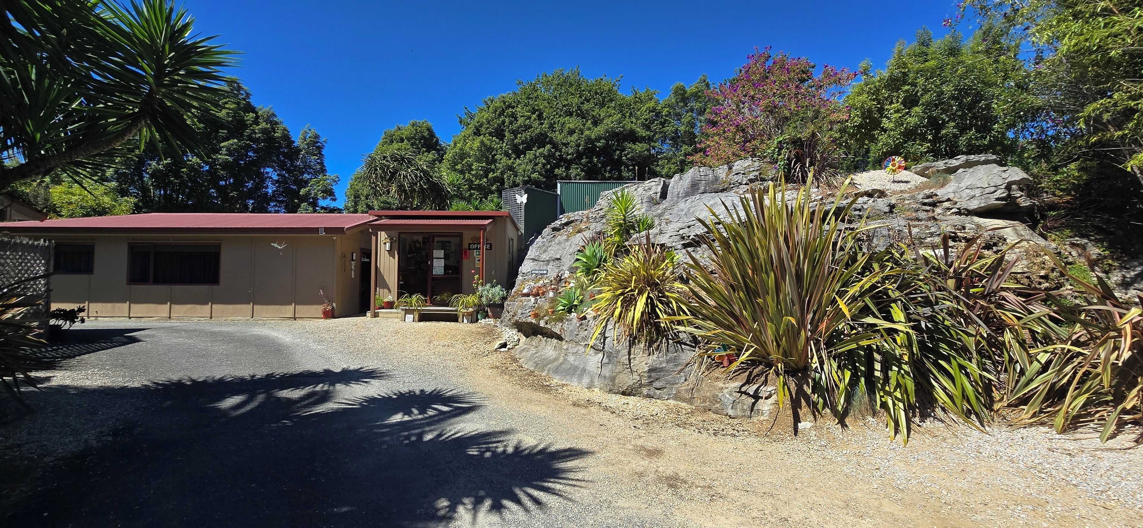 A building with a red roof, a small porch, and a gravel driveway.
