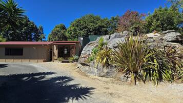 A building with a red roof, a small porch, and a gravel driveway.