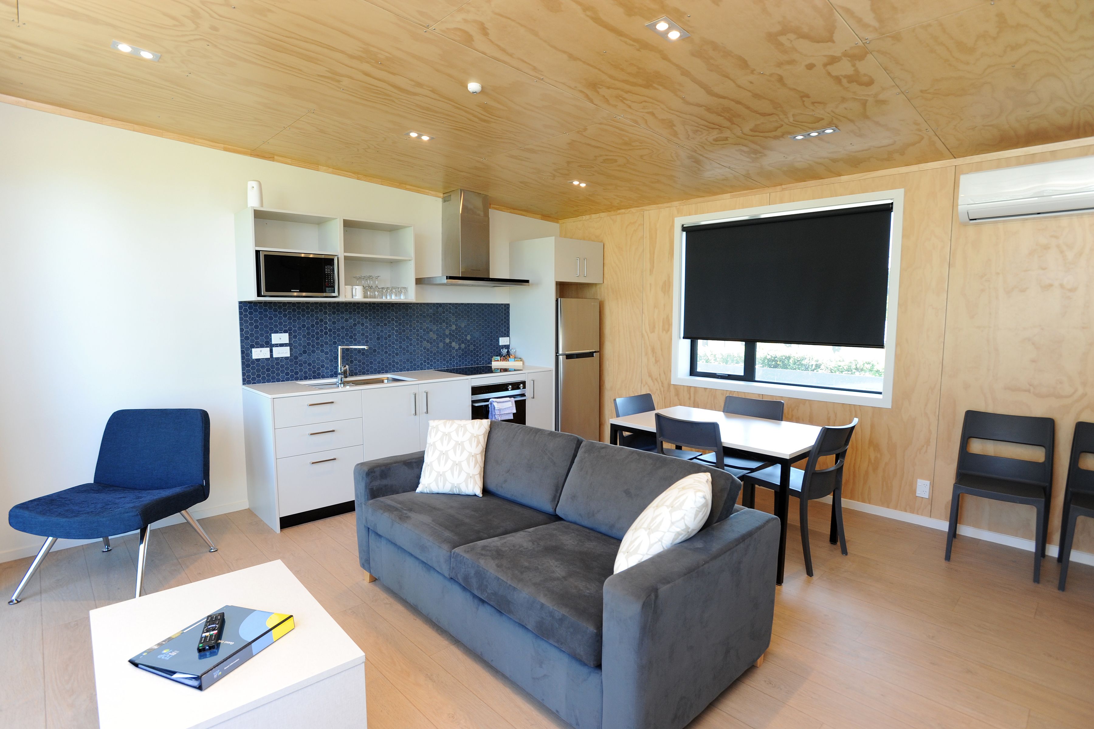 A compact living space with a kitchenette, a sofa, a dining table, and a TV.