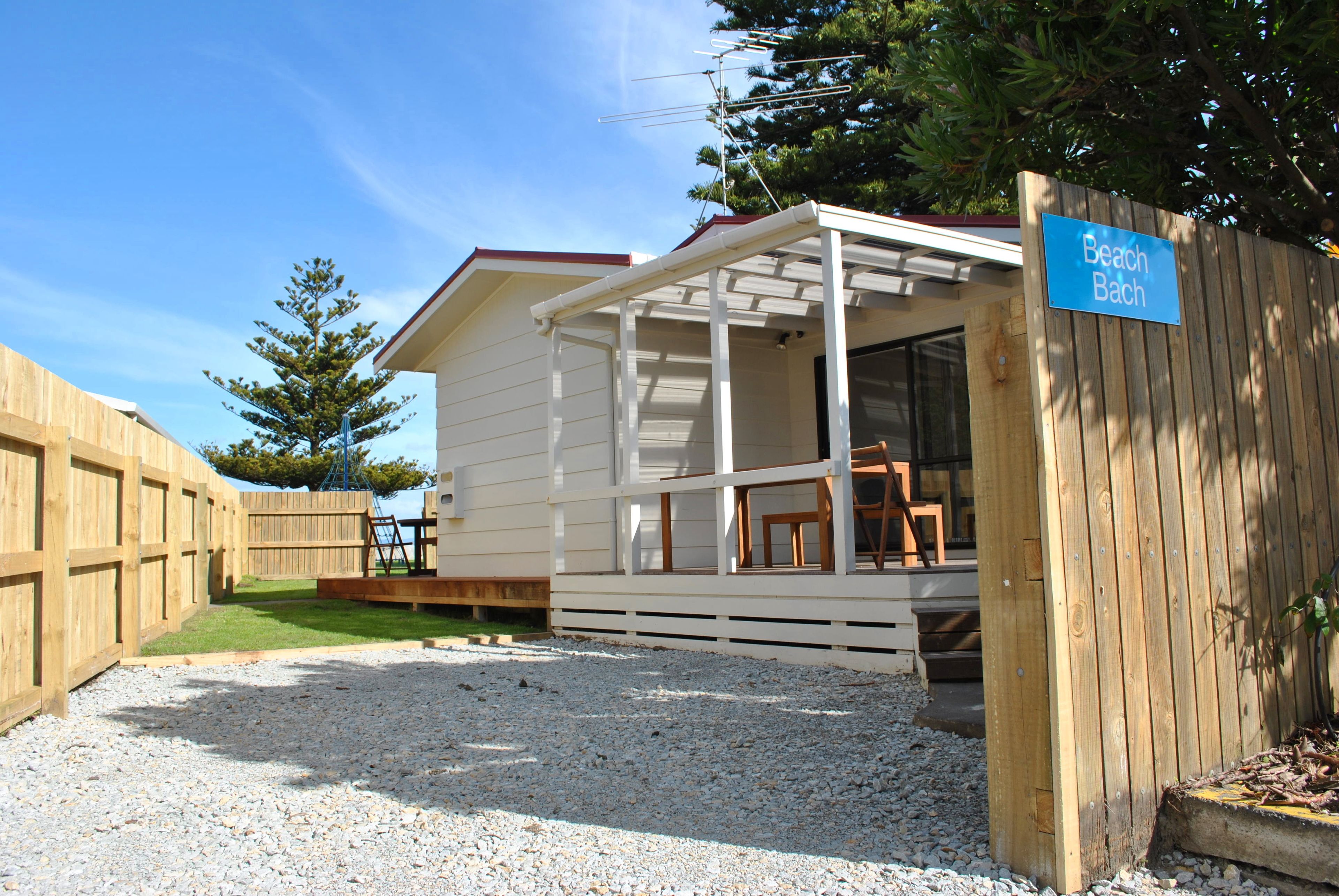A small, single-story wooden building with a covered porch and a sign reading "Beach Bach."