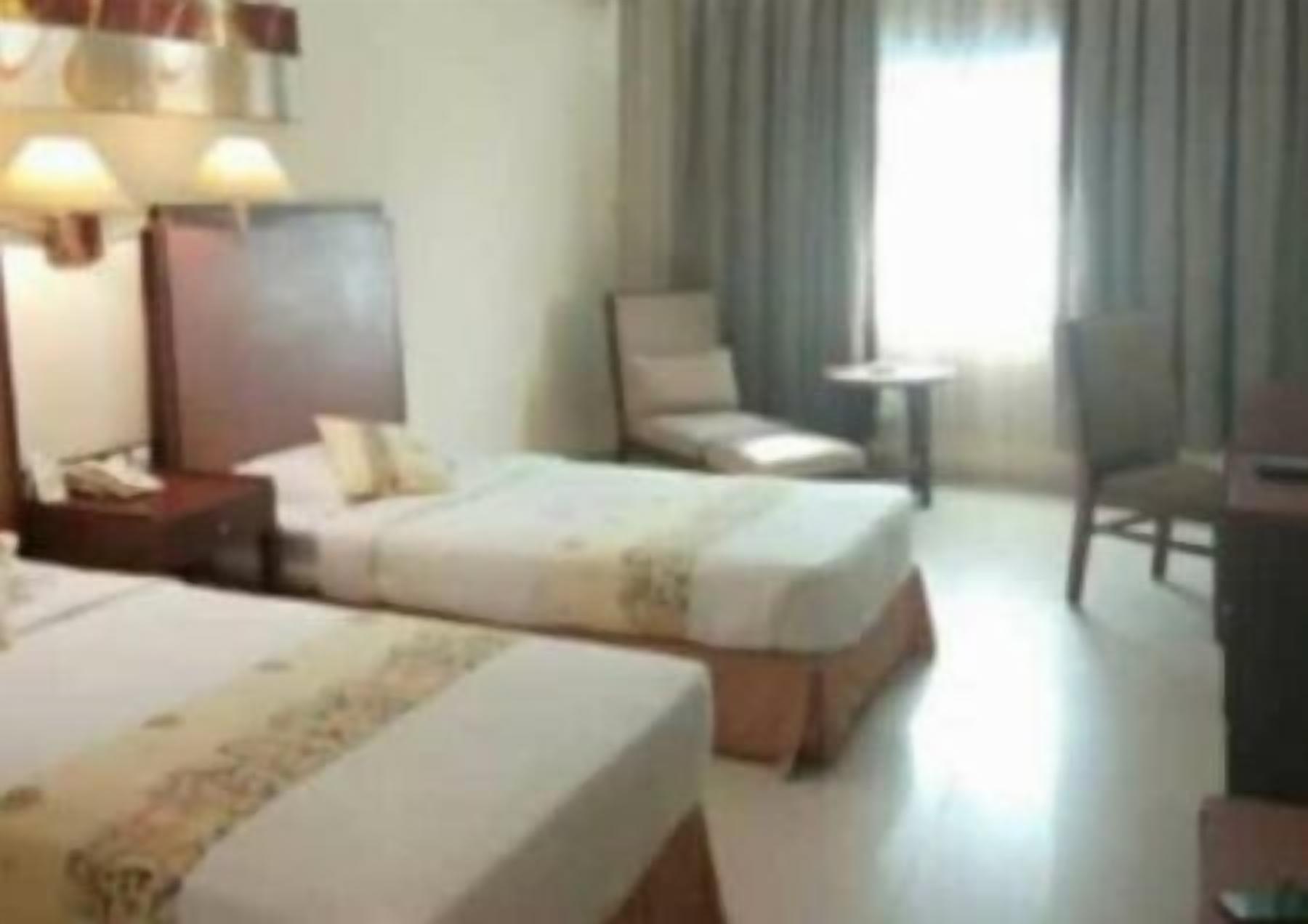 Una habitación de hotel con dos camas, un escritorio, una silla y una mesita.