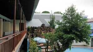 Zwembadgedeelte met een boom, parasols en een gebouw met balkon.