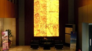 Een moderne lobby met een grote, verlichte wand, een zithoek en een receptiebalie.