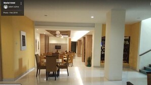 Een moderne hotel lobby met een ruime eetruimte, een flatscreen televisie aan de muur en een trap die naar een ander niveau leidt.