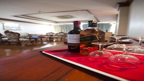 A hotel room with a dining table set for a meal, featuring a bottle of wine and glasses. - Angkham Hotel (Vientiane)