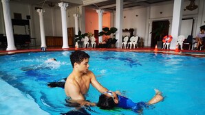 A swimming pool with a person assisting another in the water. - Angkham Hotel (Vientiane)