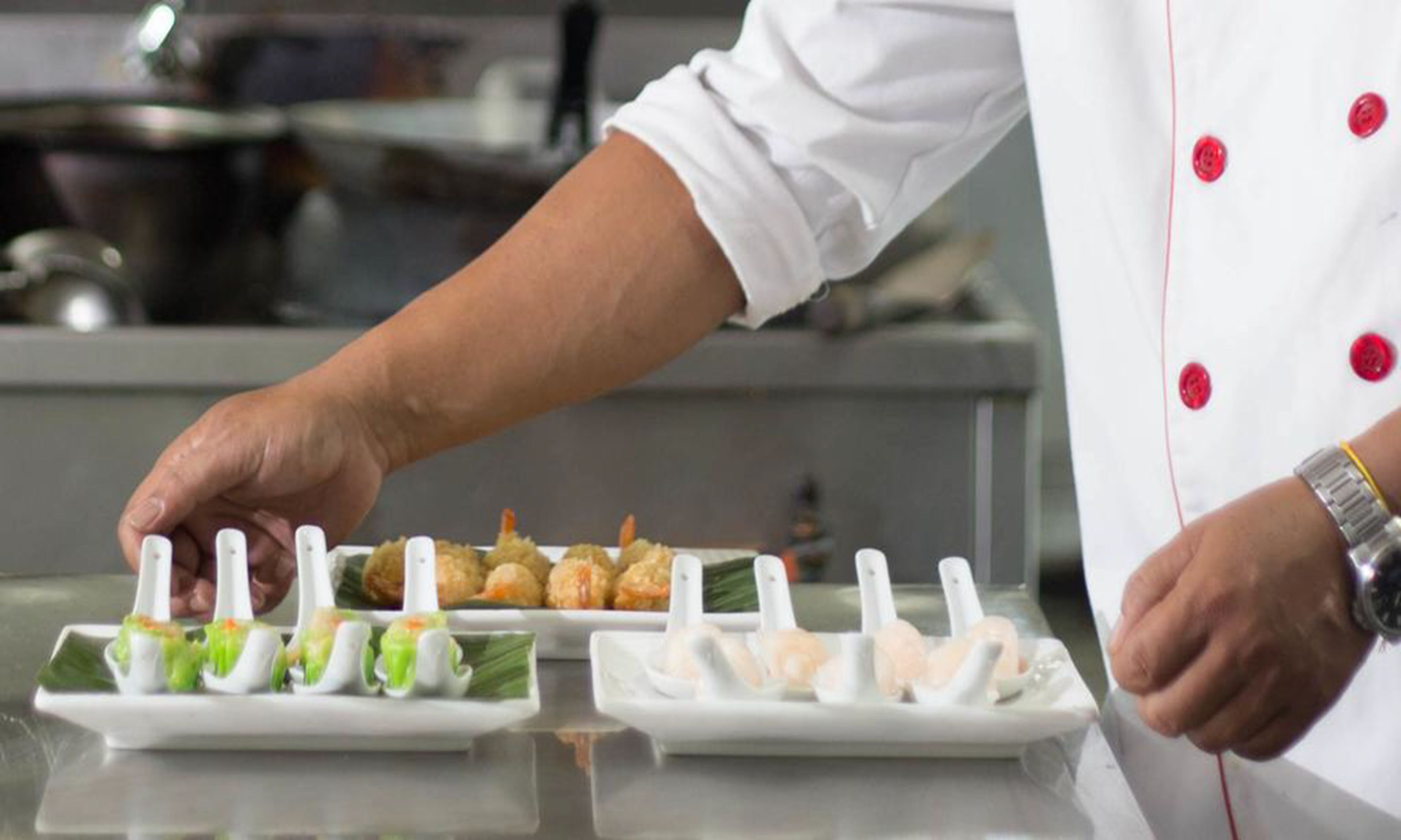 Una mano de chef colocando comida en una bandeja.