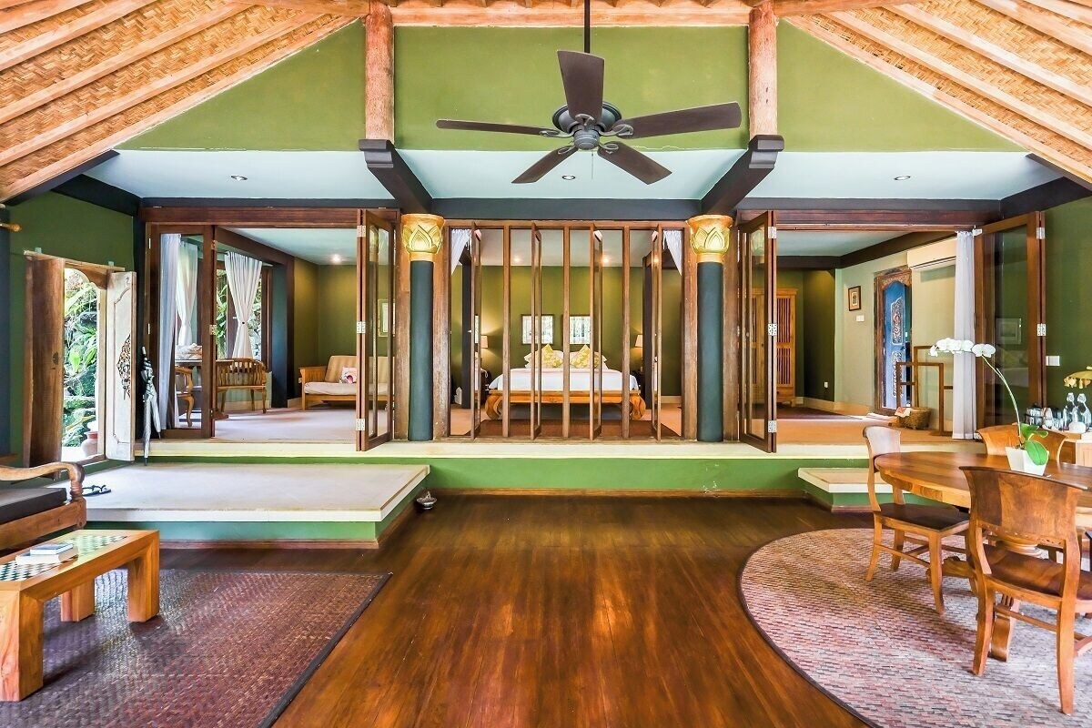 Una habitación amplia con una cama grande, muebles de madera y un ventilador de techo.