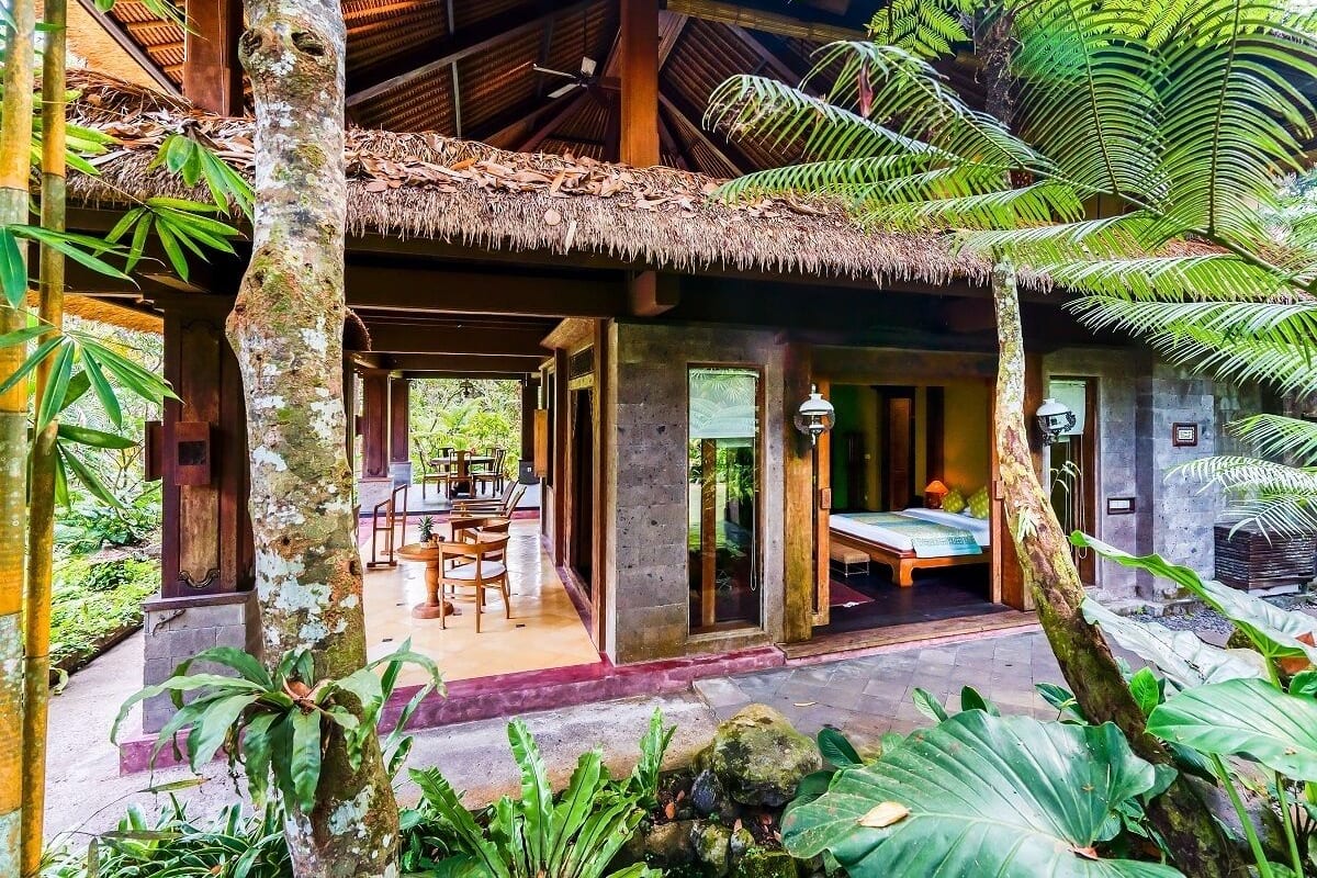 A traditional wooden structure with a thatched roof, a bed, and a dining area.