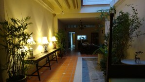 A hallway with a tiled floor, a dining area with a table and chairs, and potted plants.