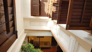 A narrow, enclosed stairwell with wooden shutters and a small plant in the center.