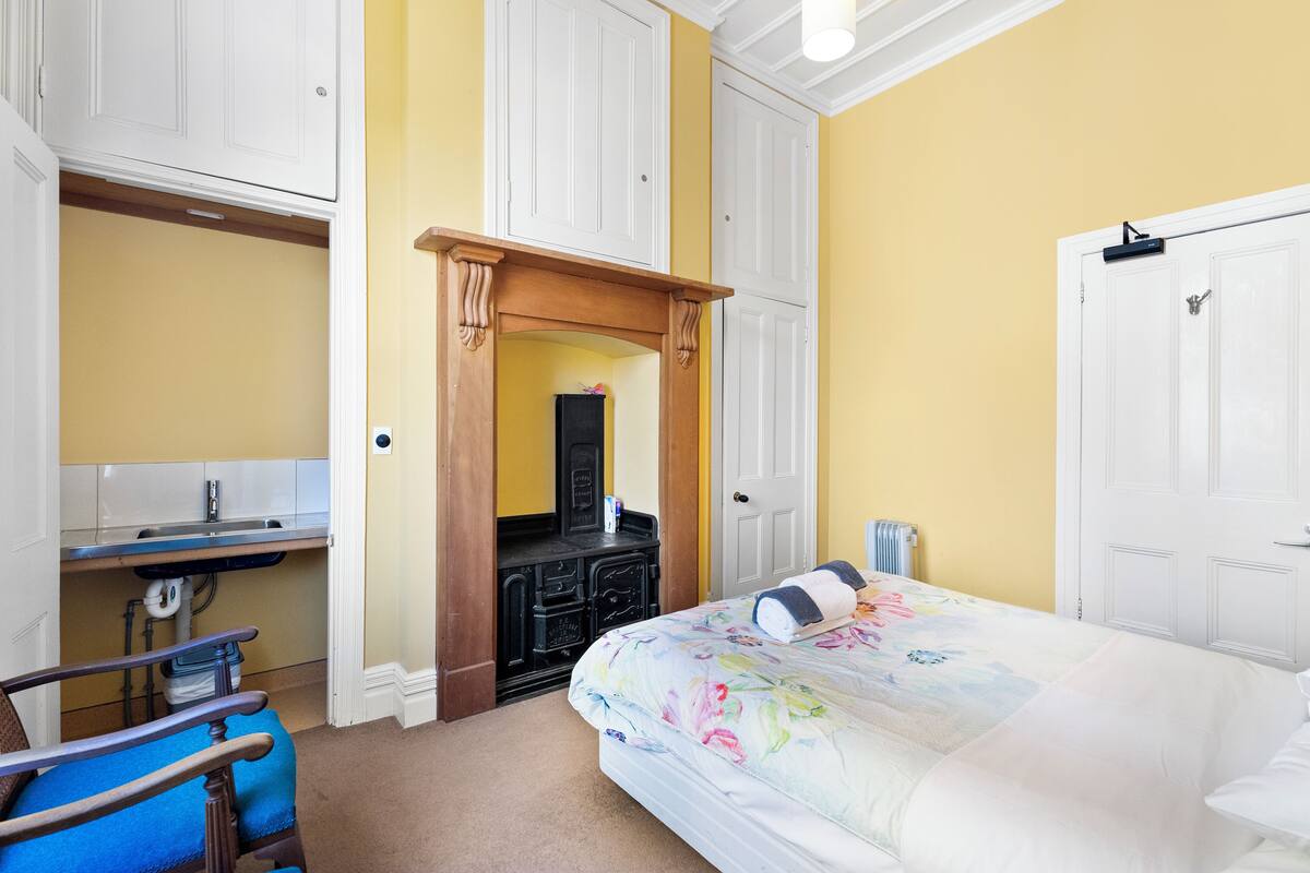 A bedroom with a bed, a dresser, a chair, and a desk.